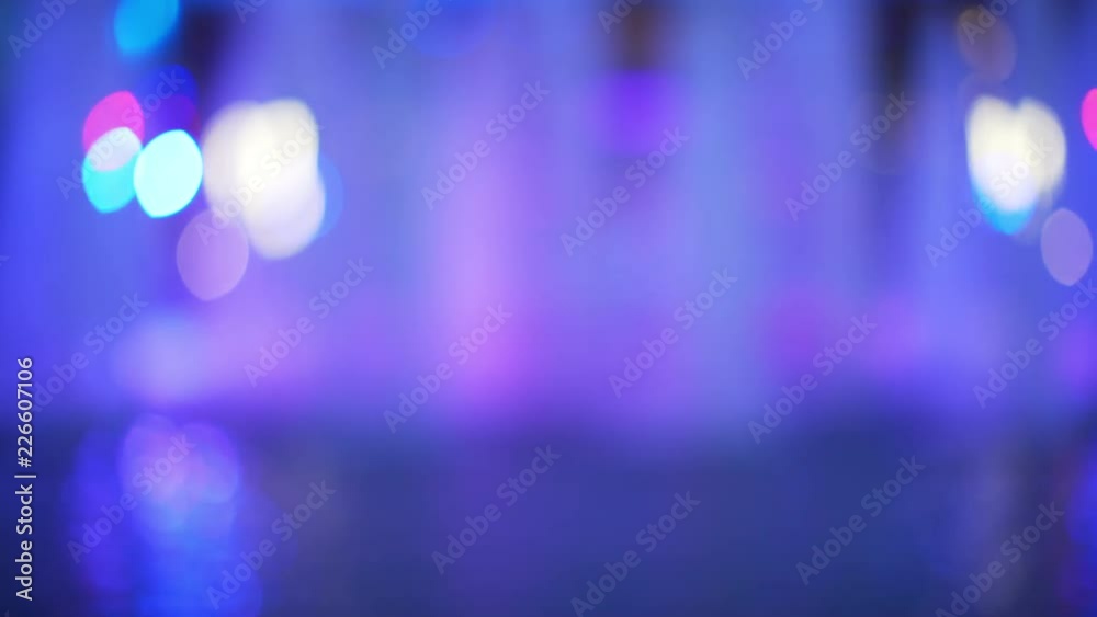 Moving shot with purple and blue water feature with glowing bokeh behind it for green screen or chroma key. Out of focus or defocused shot for compositing or keying. 
