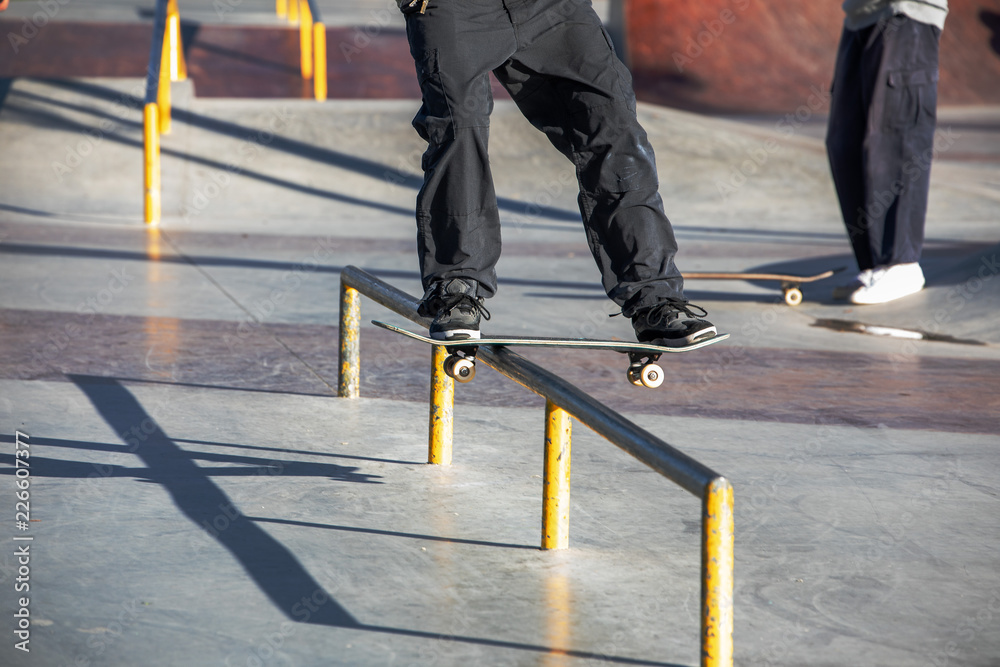 Teen skater slides over a railing on a skateboard in a skate park Stock ...