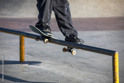 Teen skater slides over a railing on a skateboard in a skate park photo