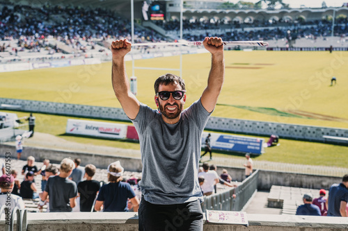.Young man enjoying a rugby match at the stadium on a sunny autumn day. Screaming, celebrating and encouraging your team. Lifestyle.