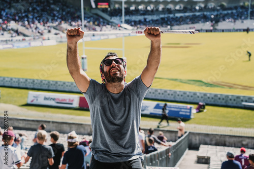 .Young man enjoying a rugby match at the stadium on a sunny autumn day. Screaming, celebrating and encouraging your team. Lifestyle.