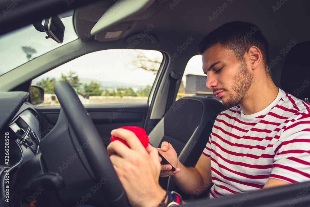 Guy in a car with coffee and phone Guy in a car with coffee and phone