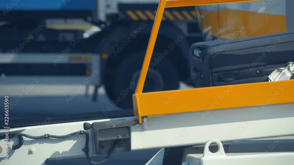 Luggage - suitcases and bags travel along the baggage tape from an airplane to a cargo car to be sent to the airport terminal. Luggage - suitcases and bags travel along the baggage tape from an airplane to a cargo car to be sent to the airport terminal.