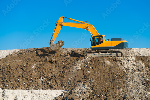 Construction of the road. Excavator (modified photo) levels the mound of sand.