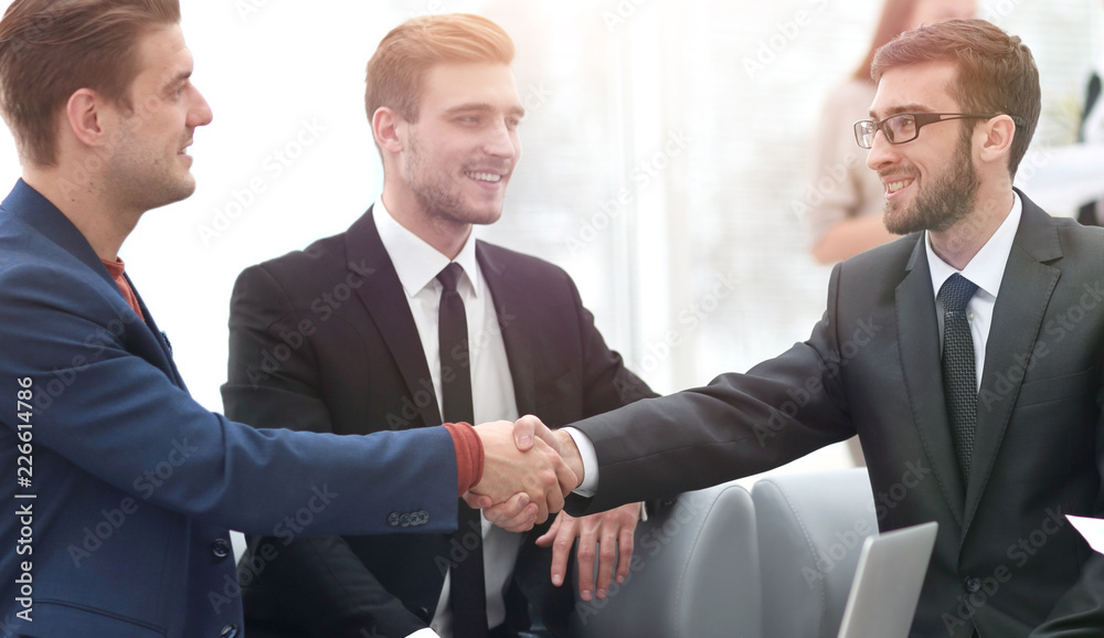 Partners concluding deal and shaking hands in the presence of team members Partners concluding deal and shaking hands in the presence of team members