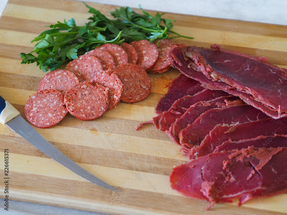 sliced turkish sausage and bacon on cutting board. Knife, sausage and bacon on wood sliced turkish sausage and bacon on cutting board. Knife, sausage and bacon on wood