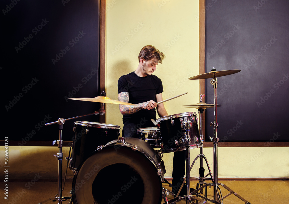 Fototapeta premium Tattooed man playing drums in studio