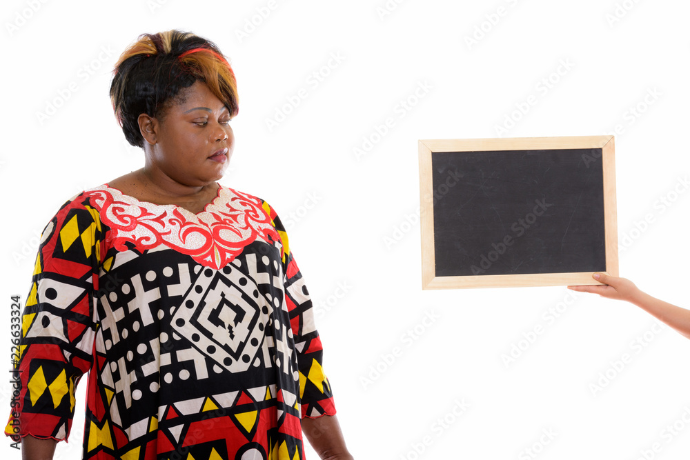 Studio shot of fat black African woman looking at blank blackboa Studio shot of fat black African woman looking at blank blackboa
