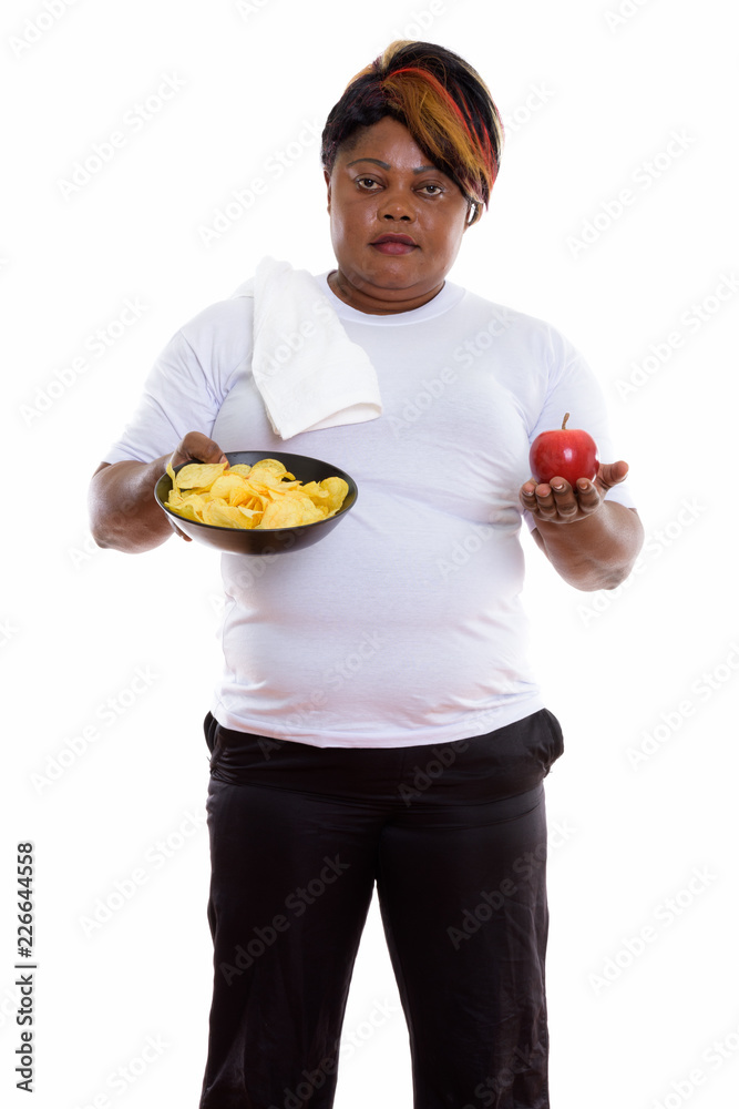 Studio shot of fat black African woman standing while holding bo Studio shot of fat black African woman standing while holding bo