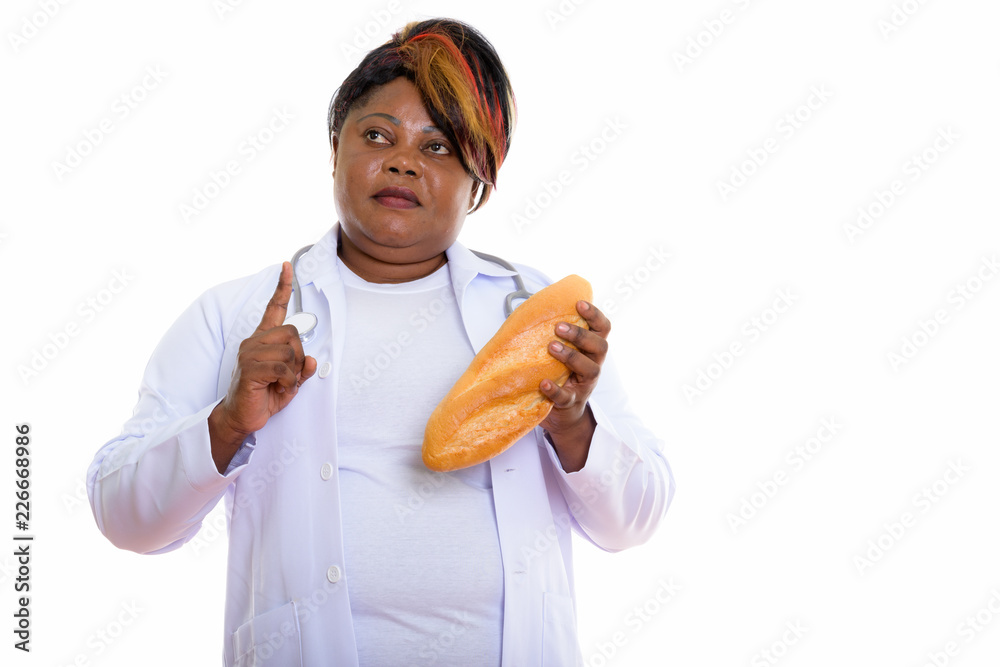 Thoughtful fat black African woman doctor holding bread and poin Thoughtful fat black African woman doctor holding bread and poin