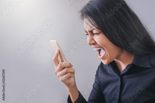 Business woman shouting to smartphone being annoyed look seriously emotion.