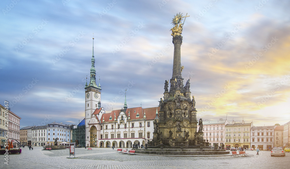 Panorama of the Square and the Holy Trinity Column enlisted in the Unesco world heritage list and Astronomical clock in the building of the Town Hall in Olomouc, Czech Republic at sunset