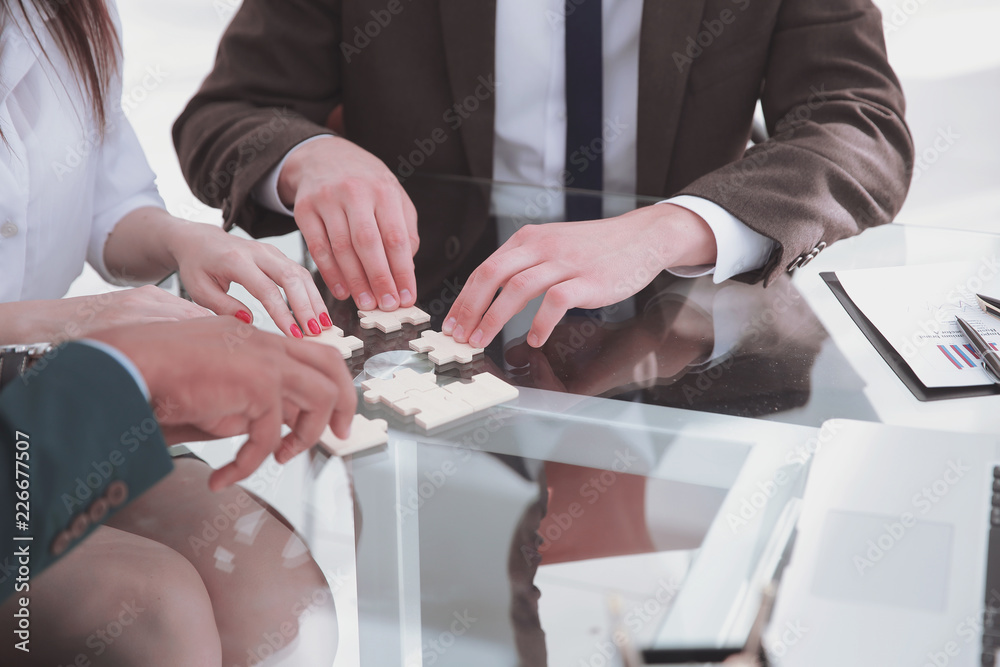 Fototapeta premium closeup .business team assembling puzzle sitting behind a Desk