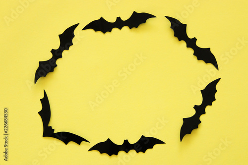 Halloween holiday concept. Black bats over yellow background. Top view, flat lay.