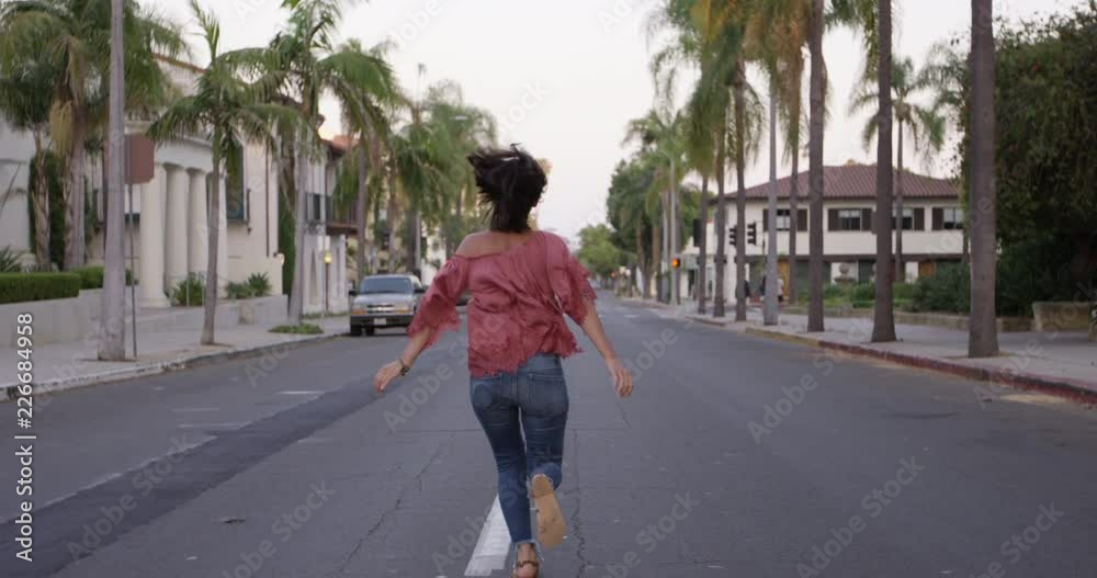 Beautiful young woman traveller running down California street - wide shot Beautiful young woman traveller running down California street - wide shot