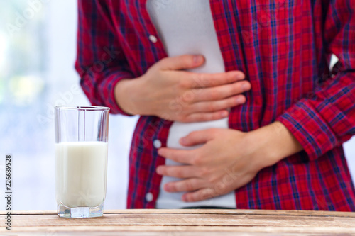 A woman feels bad, has an upset stomach, bloating due to lactose intolerance. Dairy intolerant person. Health care concept. Lactose intolerance and dairy products