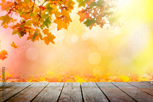Multi colored autumn leaves bokeh background over wooden deck 