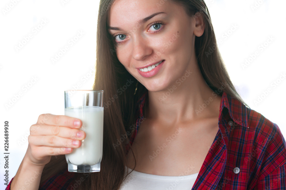 A young, attractive, smiling woman holds in her hands a glass of fresh milk. Dairy products A young, attractive, smiling woman holds in her hands a glass of fresh milk. Dairy products