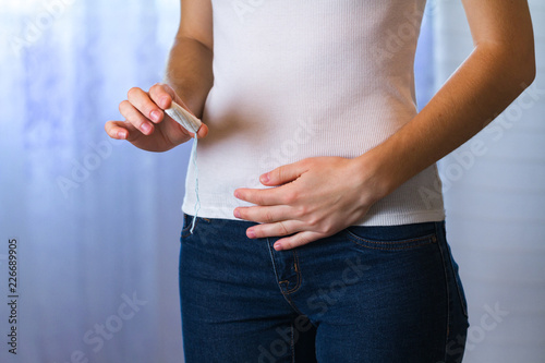 Pain, feeling sick during critical days. Young woman holding a tampon. Women's and gynecological health care. Menstrual cycle. Hygiene care during critical days. Tampon woman. Gynecological health