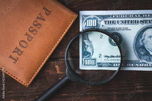 American hundred dollars, passport and magnifier on a wooden table. Money concept, financial concept.