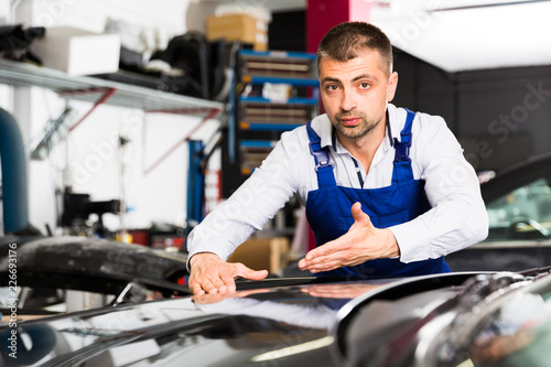 Male worker showing car after repainting