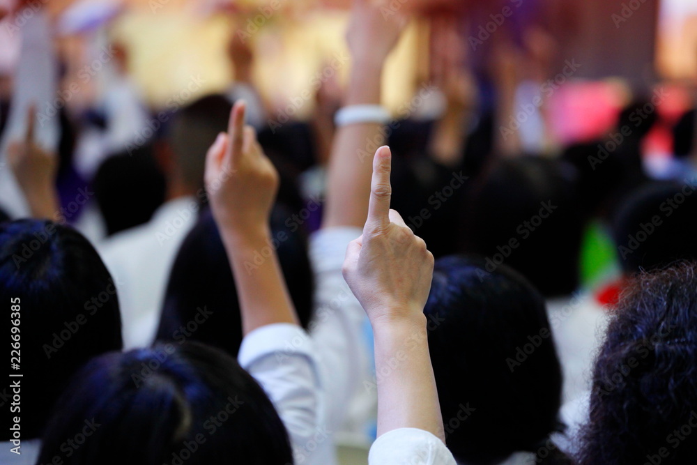 people reacting to the question by raising their index finger together as teamwork for unity and unanimous agreement and collaboration in the classroom - obrazy, fototapety, plakaty 