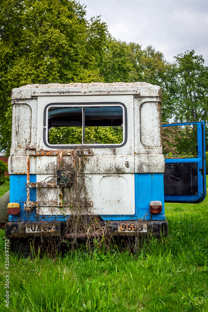 Abandoned vintage car blue lush green grass broken glass