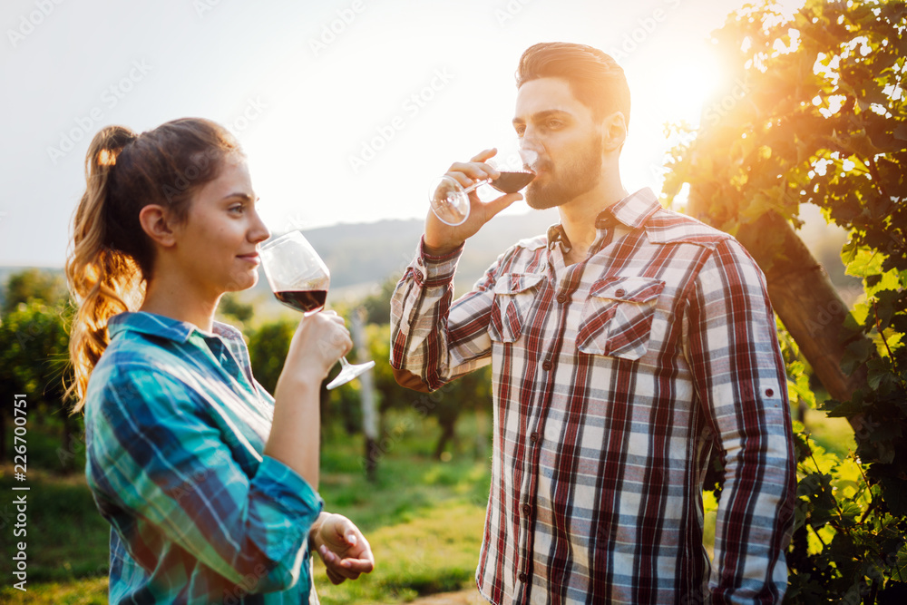 Naklejka premium Wine growers tasting wine in vineyard