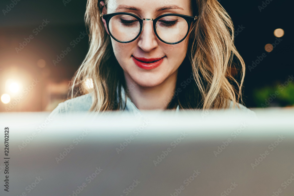 Portrait of young business woman in trendy glasses sitting in cafe,working on laptop.Blogger communicates with followers