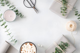 Lifestyle minimal frame white background with presents, chocolate with marshmallow and plants. The concept of wintertime and New Year. Flat lay, top view, copy space.
