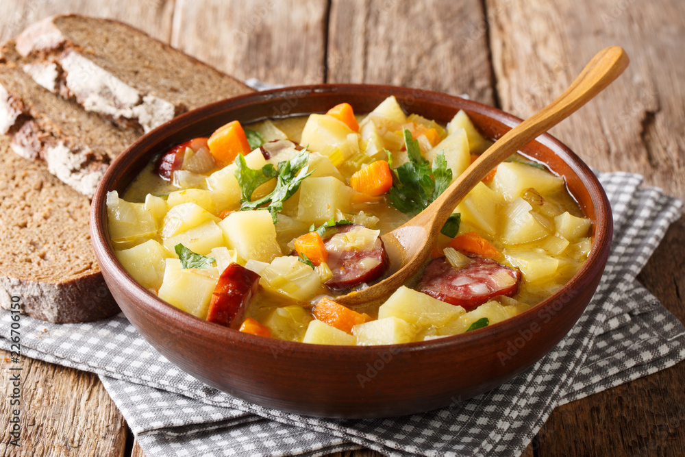 Thick potato soup with sausages and parsley in a bowl with bread close-up. horizontal Thick potato soup with sausages and parsley in a bowl with bread close-up. horizontal