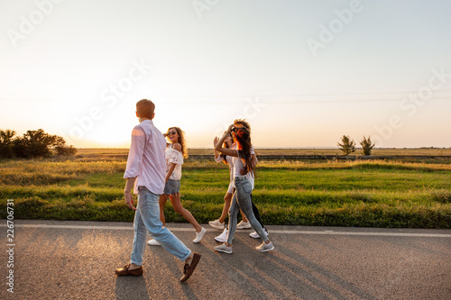 Company of happy young stylish guys walk along the road. on a sunny day