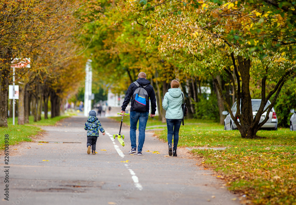 Parents walk with their son on autumn street