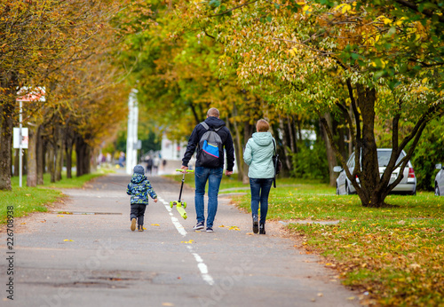 Parents walk with their son on autumn street © licvin