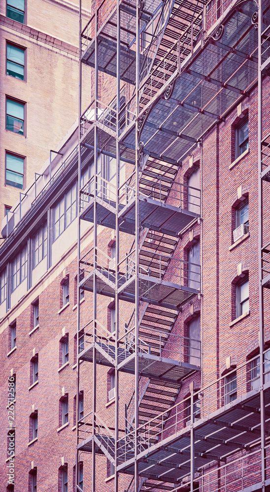 Fototapeta premium Vintage toned photo of a residential building fire escape in Manhattan, New York City, USA.
