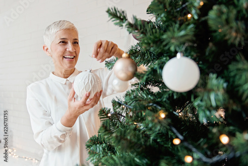 Beautiful woman decorating a Christmas tree 