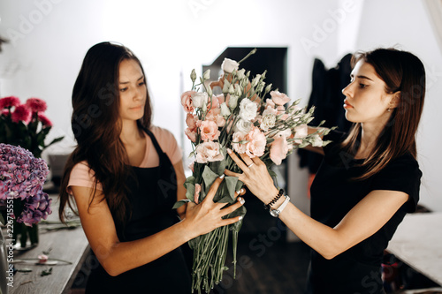 Two girls florists hold a bouquet of eustoms in pastel colors photo