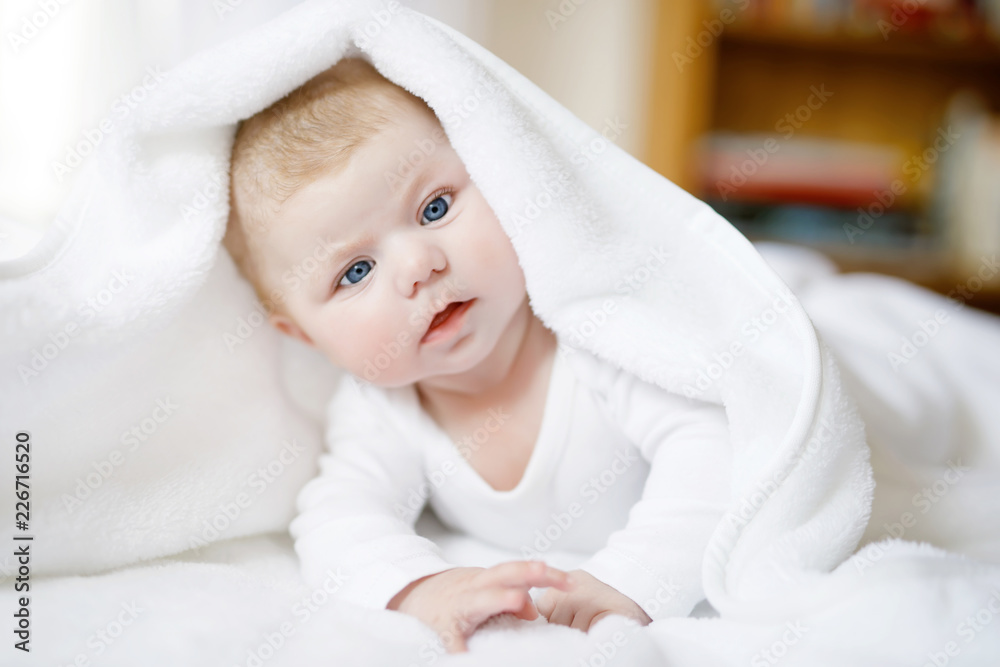 Baby girl wearing white towel or winter overal in white sunny bedroom Baby girl wearing white towel or winter overal in white sunny bedroom