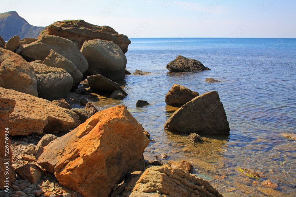 View to the Black sea in sunny summer day, huge stones in the shore