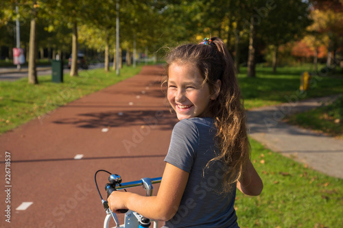 Happy child rides a bike on bike path.