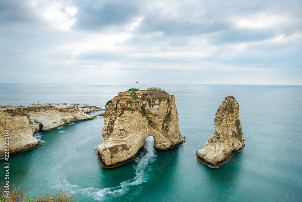 Fototapeta premium Rouche skały w Bejrucie w Libanie w pobliżu morza i podczas zachodu słońca. Pochmurny dzień w Bejrucie w Libanie na Pigeon Rocks na Morzu Śródziemnym.