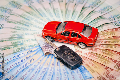 Toy car with a real key, lie on a pile of banknotes of the Russian Federation. The concept of buying a new car.