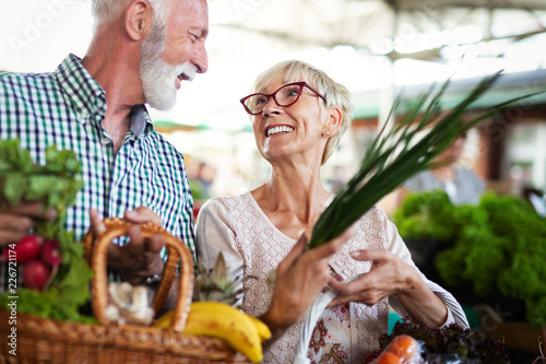 Smiling senior couple buying vegetables and at the merket photo
