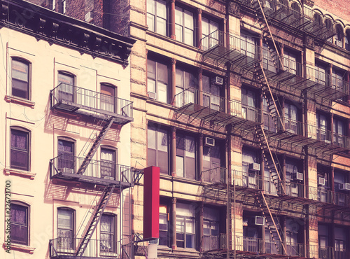 Old buildings with fire escapes in New York City, color toning applied, USA.