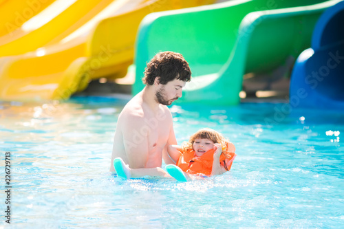 Happy family having fun together in outdoors swimming pool in water park  aquapark 