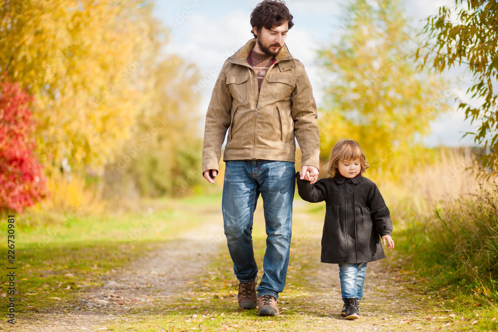 Fototapeta premium Father and daughter walking together, autumn day