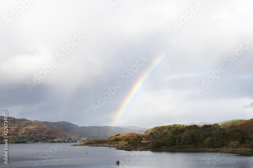 Rainbow dark storm sky and light from sum at loch melfort argyll west scotland in autumn