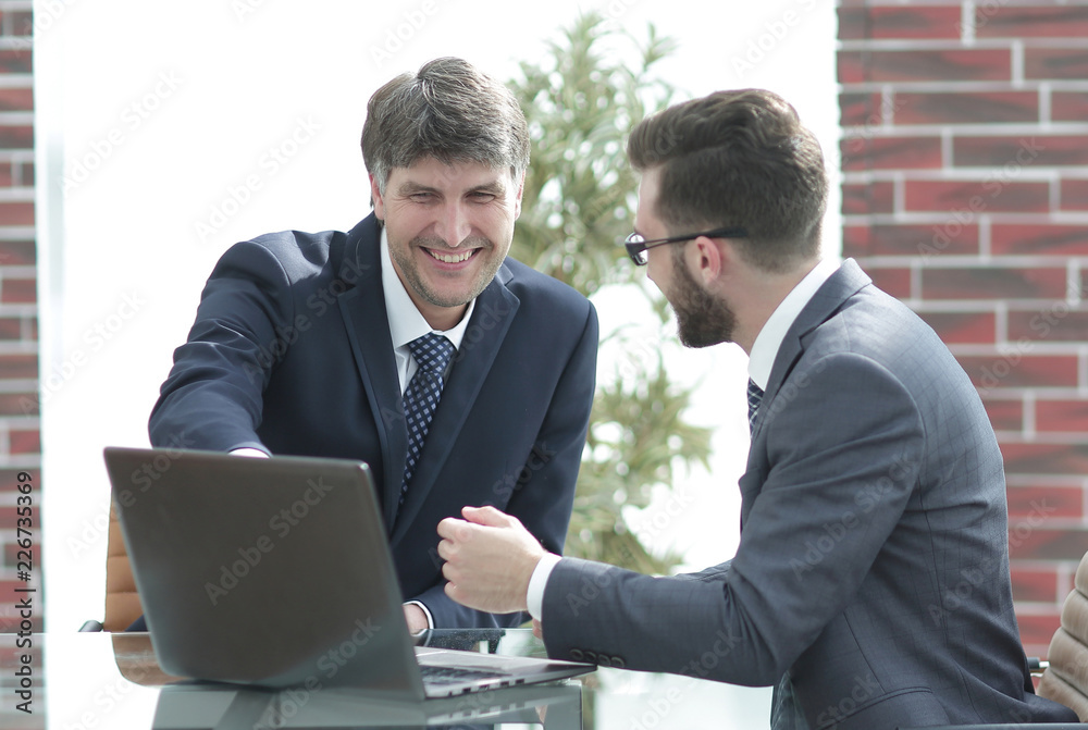 Two businessmen working together using laptop on business meeting in office Two businessmen working together using laptop on business meeting in office