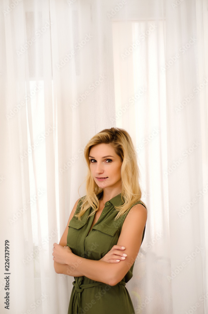 a girl in a green dress stands on a light background a girl in a green dress stands on a light background