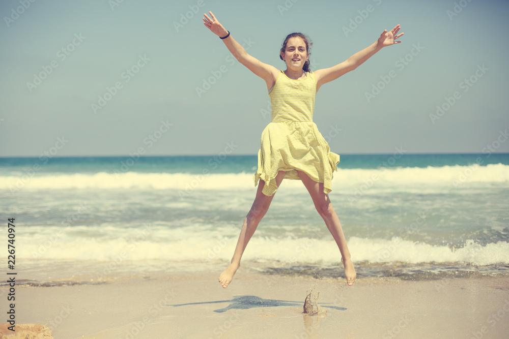 12 years old girl teen girl in yellow dress walking on seaside. Summer vacation 12 years old girl teen girl in yellow dress walking on seaside. Summer vacation